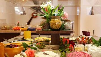 A buffet setup with various food items and a decorative vase with flowers.