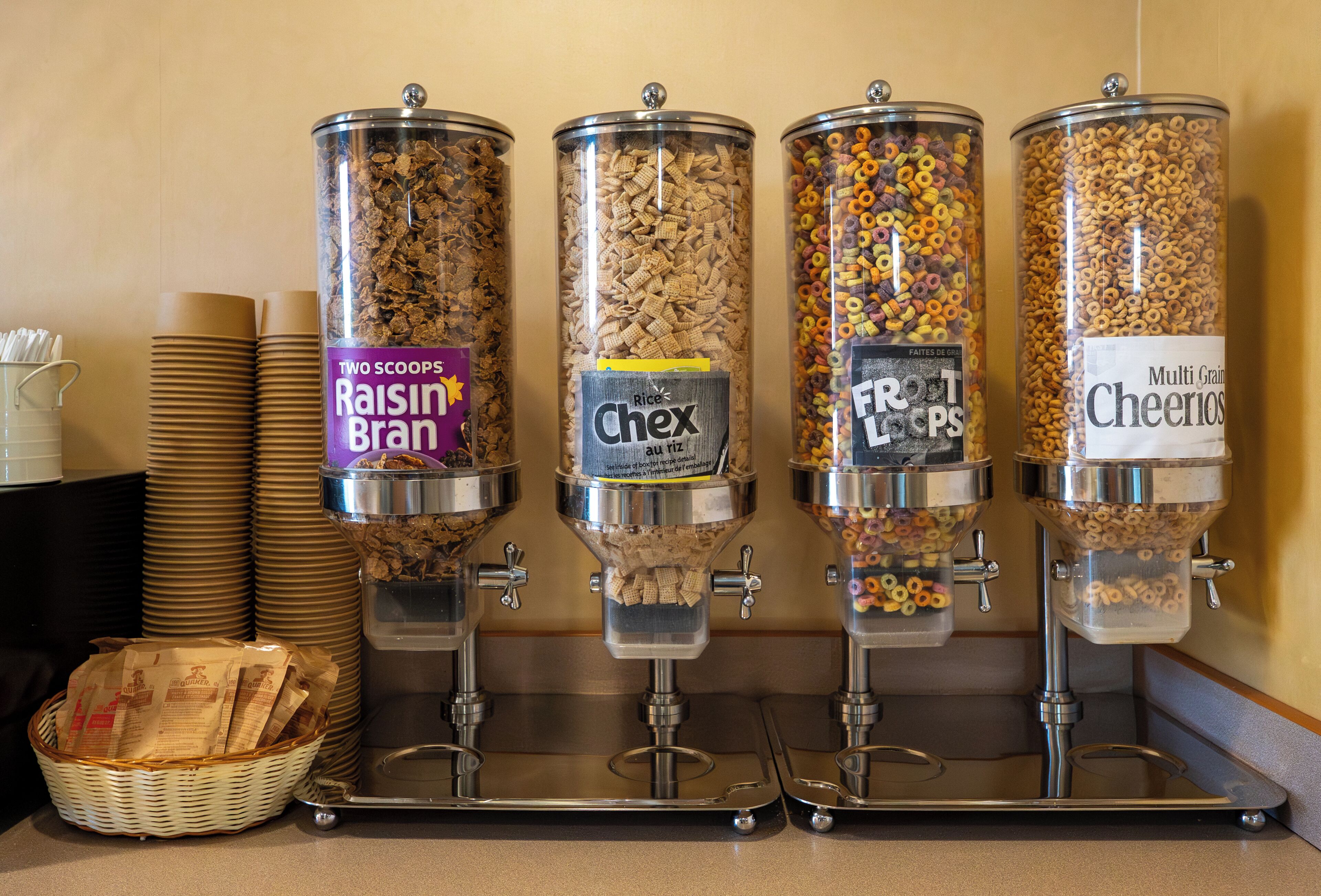 Four cereal dispensers with labels for Raisin Bran, Rice Chex, Fruity Loops, and Cheerios.