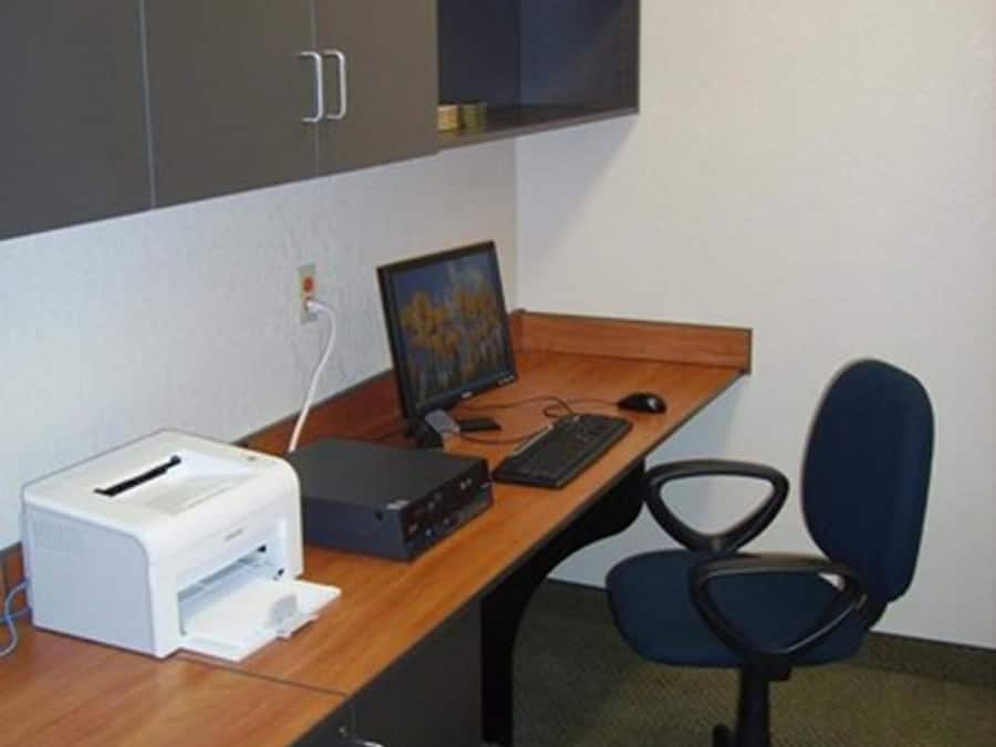 A small office with a desk, computer, printer, and a chair.