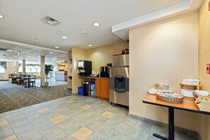 A hotel kitchen with a coffee machine, refrigerator, and buffet table.