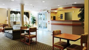 A lobby with a reception desk, seating area with chairs and sofas, a plant, and a door leading to another room. - Parry Sound Inn & Suites (Parry Sound)
