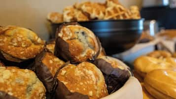 Variedad de productos horneados, como muffins y pan, expuestos en un bol y sobre una mesa.