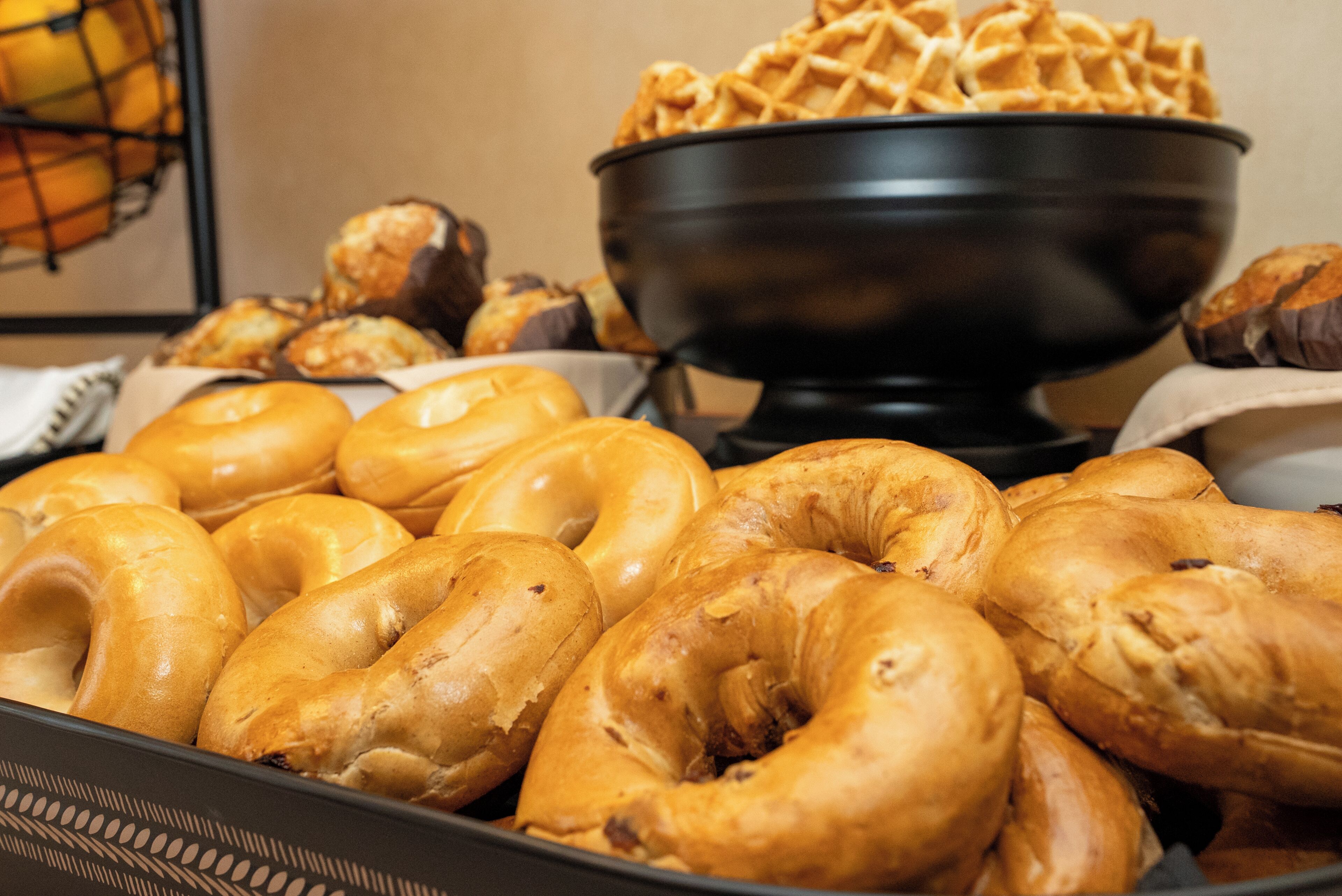 A tray of bagels and a bowl of waffles.