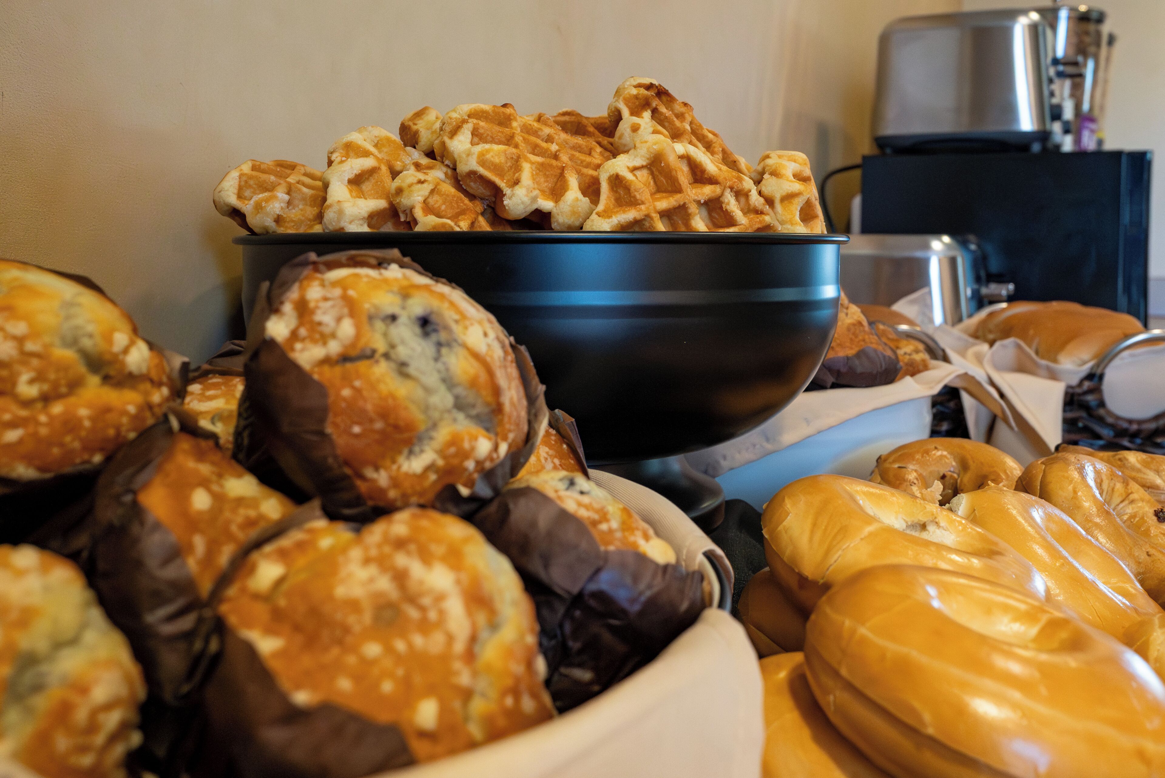 Un assortiment de produits de boulangerie, notamment des gaufres, des muffins et des pâtisseries, présentés dans un bol.
