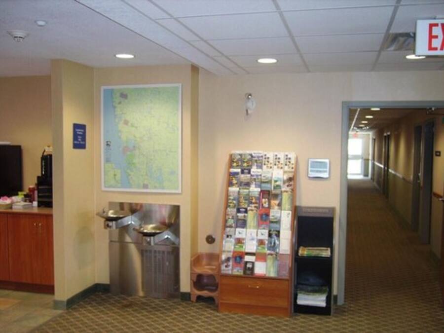 A hotel lobby with a reception desk, a map on the wall, a bulletin board, and a trash can.