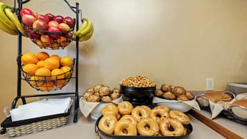 A breakfast buffet with fruits, donuts, waffles, and pastries.
