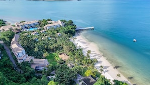 A resort with multiple buildings, a beach, and a pier extending into the ocean.