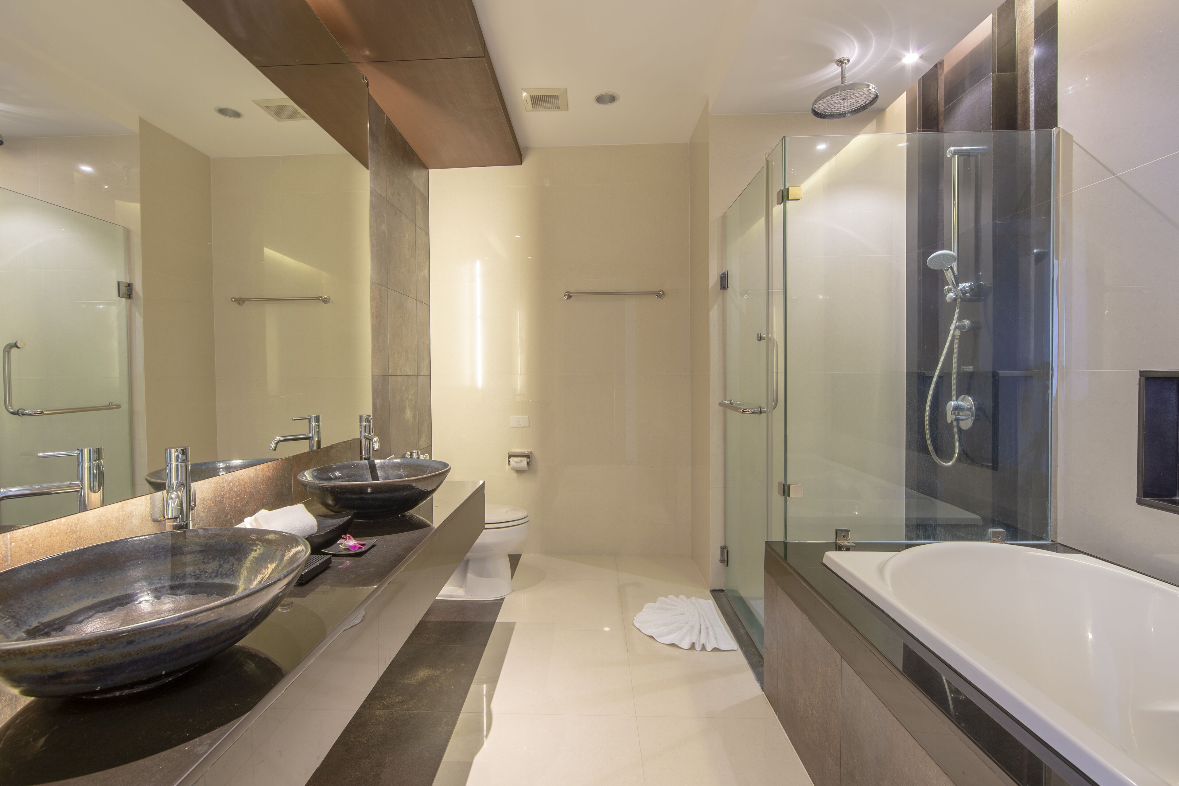 A modern bathroom with a large mirror, two sinks, a bathtub, and a glass-enclosed shower.