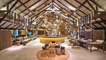 Un intérieur spacieux avec un plafond haut, un espace salon central et diverses tables et chaises.