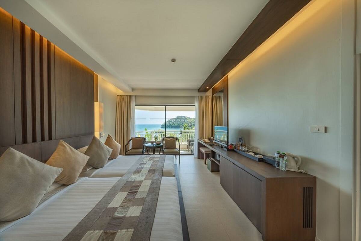 A hotel room with a large bed, a desk, and a view of the ocean.