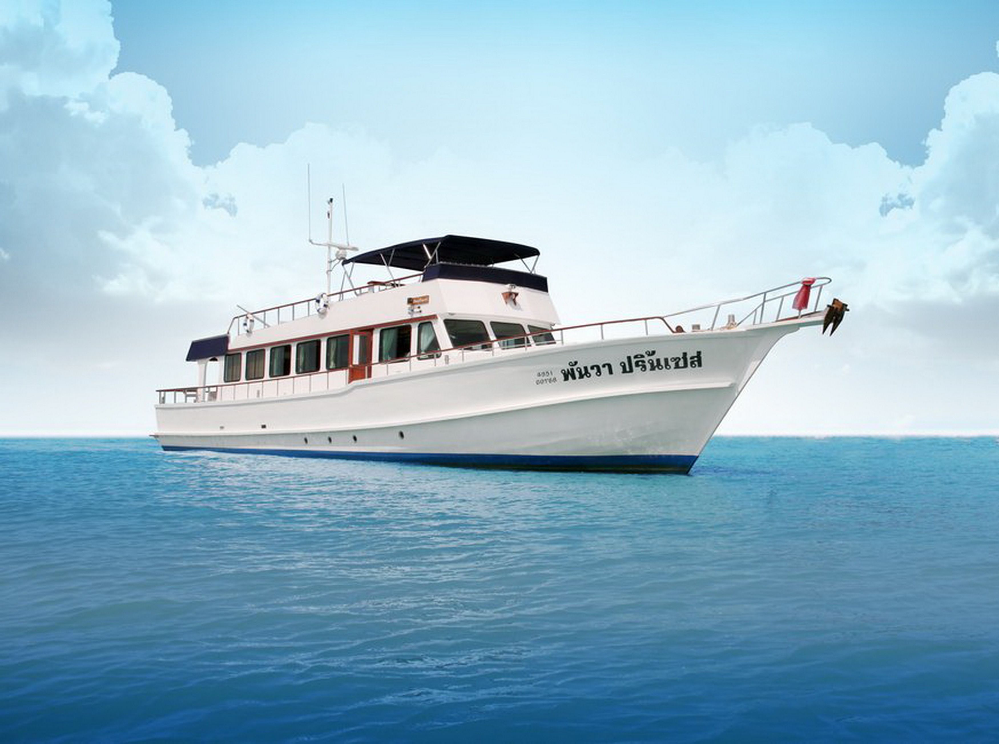 A white boat with a cabin and deck seating, sailing on calm blue waters.