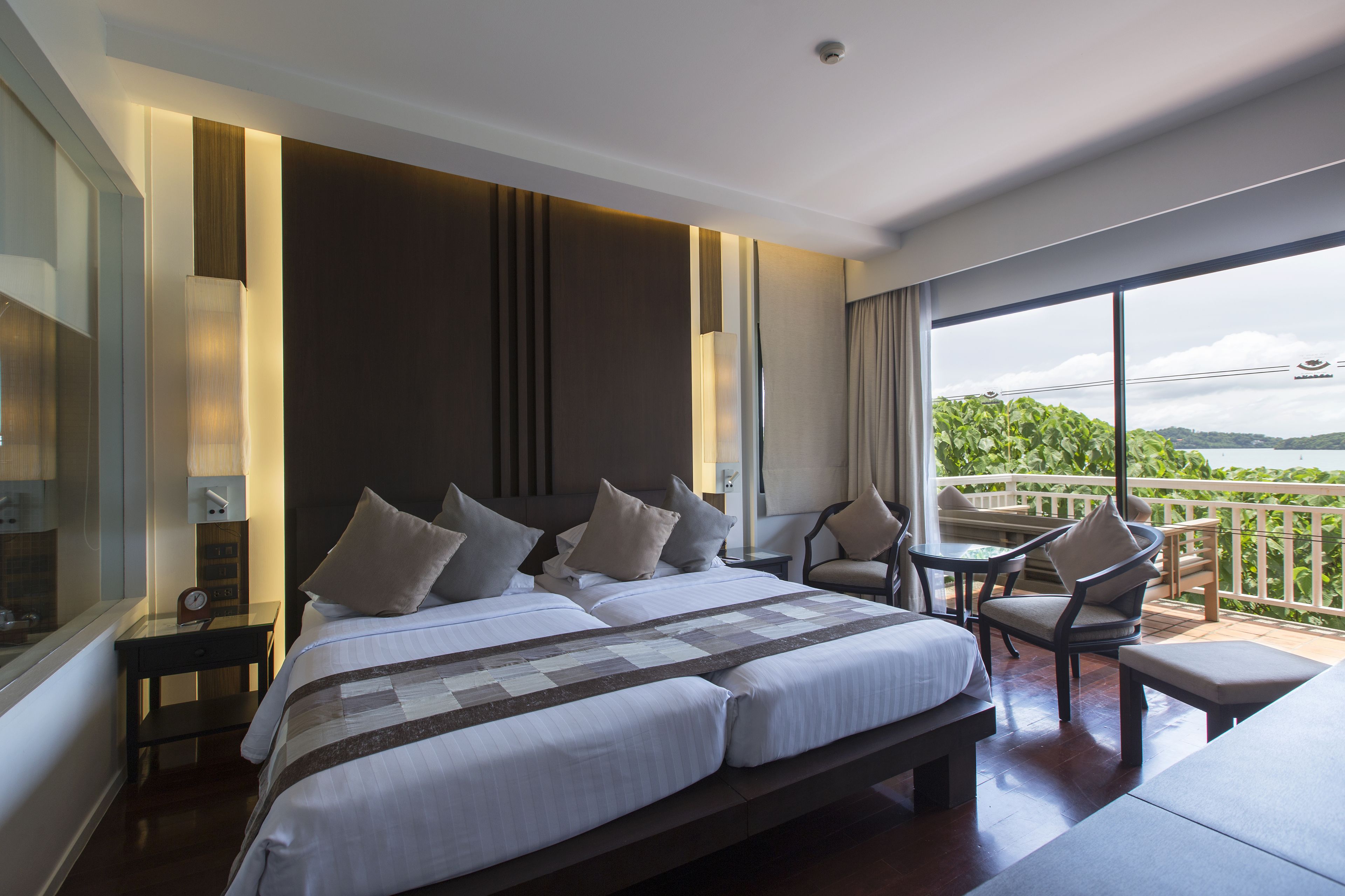 Una habitación de hotel moderna con una cama grande, un balcón con vistas y un rincón de descanso.