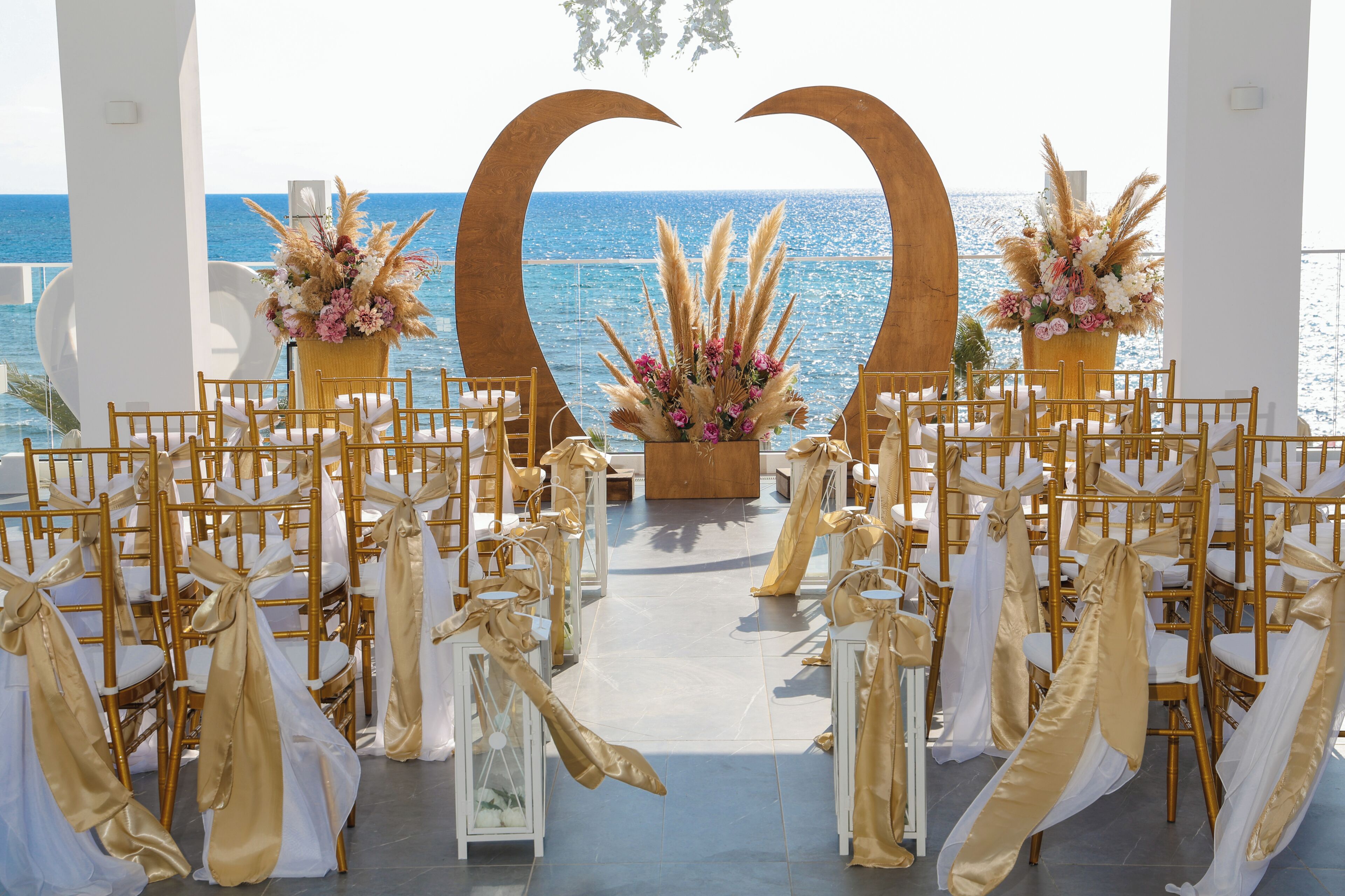An outdoor wedding venue with rows of chairs, a heart-shaped arch, and floral arrangements.