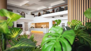 A spacious lobby with a reception desk, multiple seating areas, and a second-floor balcony. - Kefalos Beach Tourist Village (Paphos)