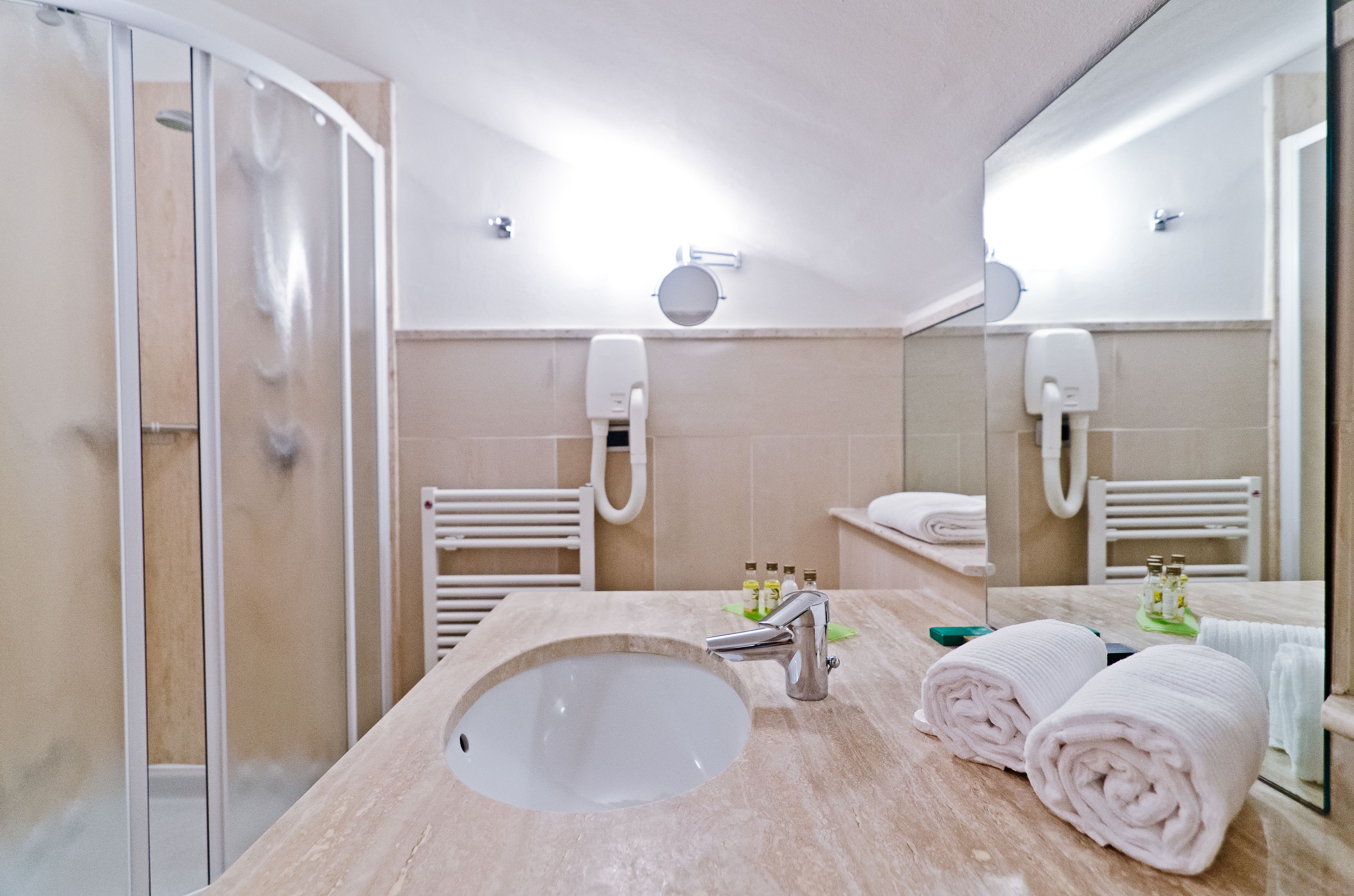 Un bagno con lavandino, specchio, porta asciugamani e zona doccia.
