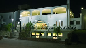 Un edificio moderno con una estructura cúpula central, varios balcones y una zona de entrada bien iluminada.