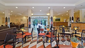 Un vestíbulo de hotel con piso a cuadros, varias zonas de estar y un mostrador de recepción.