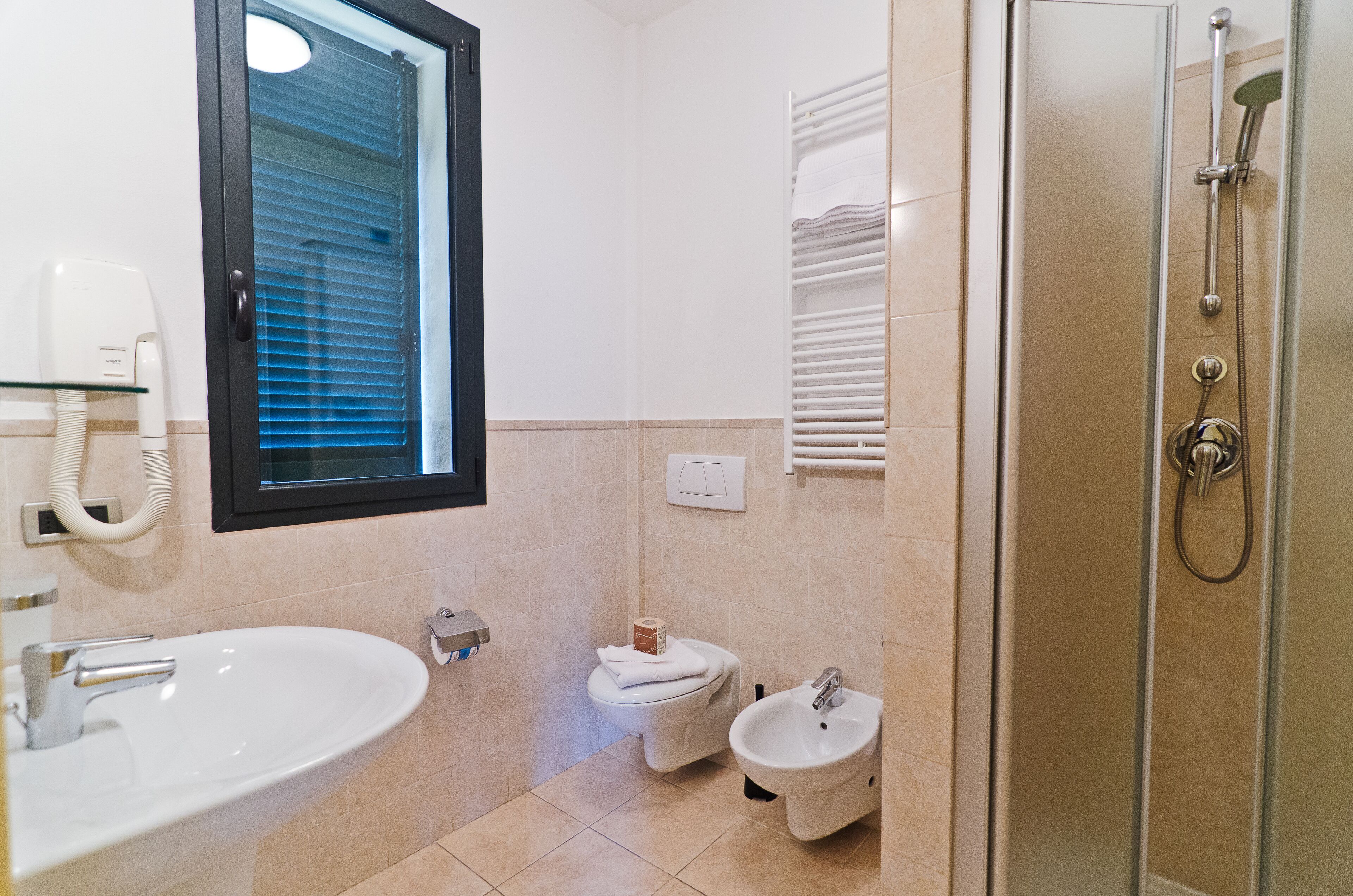 Un baño con lavamanos, inodoro, bidé y ducha.