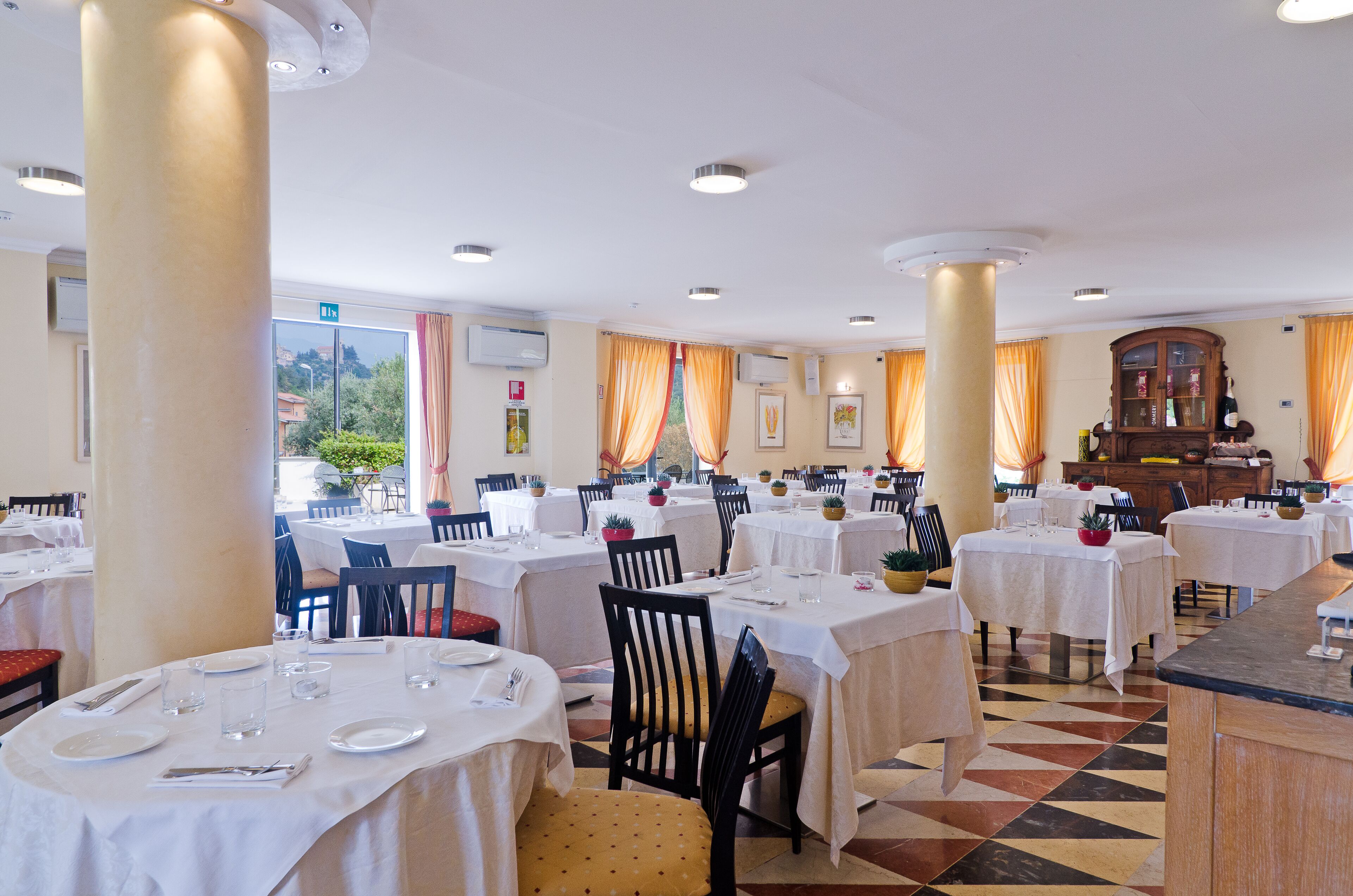 Un restaurant avec des tables rondes, des chaises et un sol à carreaux.