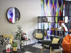 Una sala de estar moderna con un sofá, sillones, una mesa de centro, una estantería y un espejo.