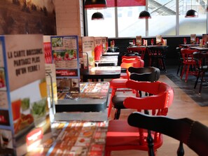 A restaurant interior with red chairs, tables, and menu boards. - ibis Styles Crolles Grenoble A41 (Crolles)