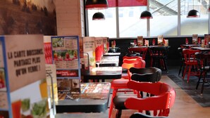 A restaurant interior with red chairs, tables, and menu boards. - ibis Styles Crolles Grenoble A41 (Crolles)