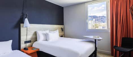 Habitación de hotel con una cama grande, una mesita de noche, una silla, una ventana con cortinas y vistas a un paisaje nevado.
