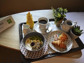 A tray with breakfast items including a bowl of cereal, a croissant, a cup of coffee, and a small plant. - ibis Styles Crolles Grenoble A41 (Crolles)
