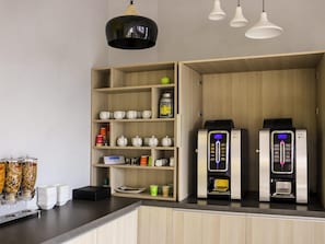 Una cocina moderna con armarios de madera, una estación de café y dos máquinas de café.