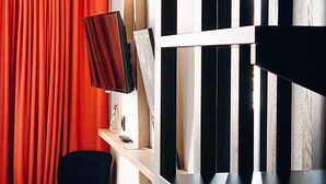 A room with a red curtain, a black chair, a desk with a computer, and a wooden bookshelf. - ibis Styles Crolles Grenoble A41 (Crolles)