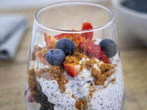 Postre en vaso transparente con fresas y arándanos.