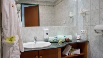 Un baño con lavamanos, espejo, toallero y artículos de aseo.