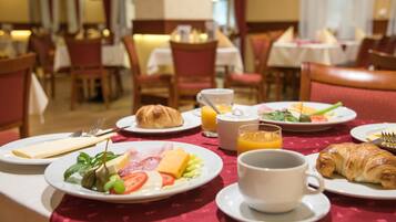 Una escena de desayuno con platos de comida, una taza de café y un vaso de zumo de naranja.