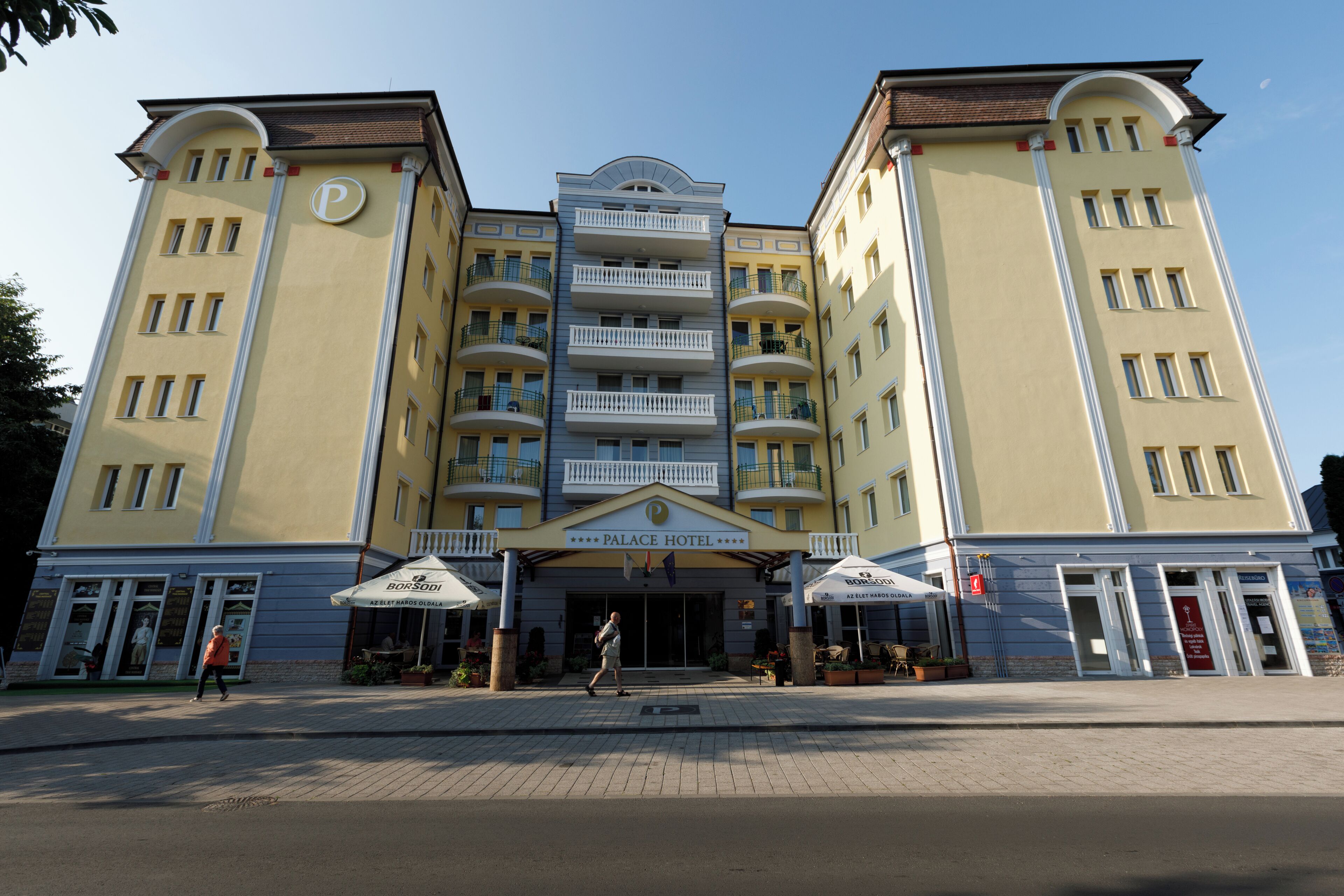 Ett hotell med flera våningar, en central entré, balkonger och en skylt som visar att det är ett hotell.