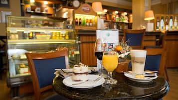 Una mesa con un postre, un vaso de jugo de naranja y una taza de café en un café.