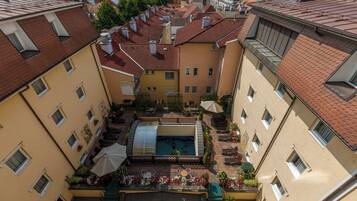 A courtyard with a swimming pool, outdoor seating, and a view of surrounding buildings.