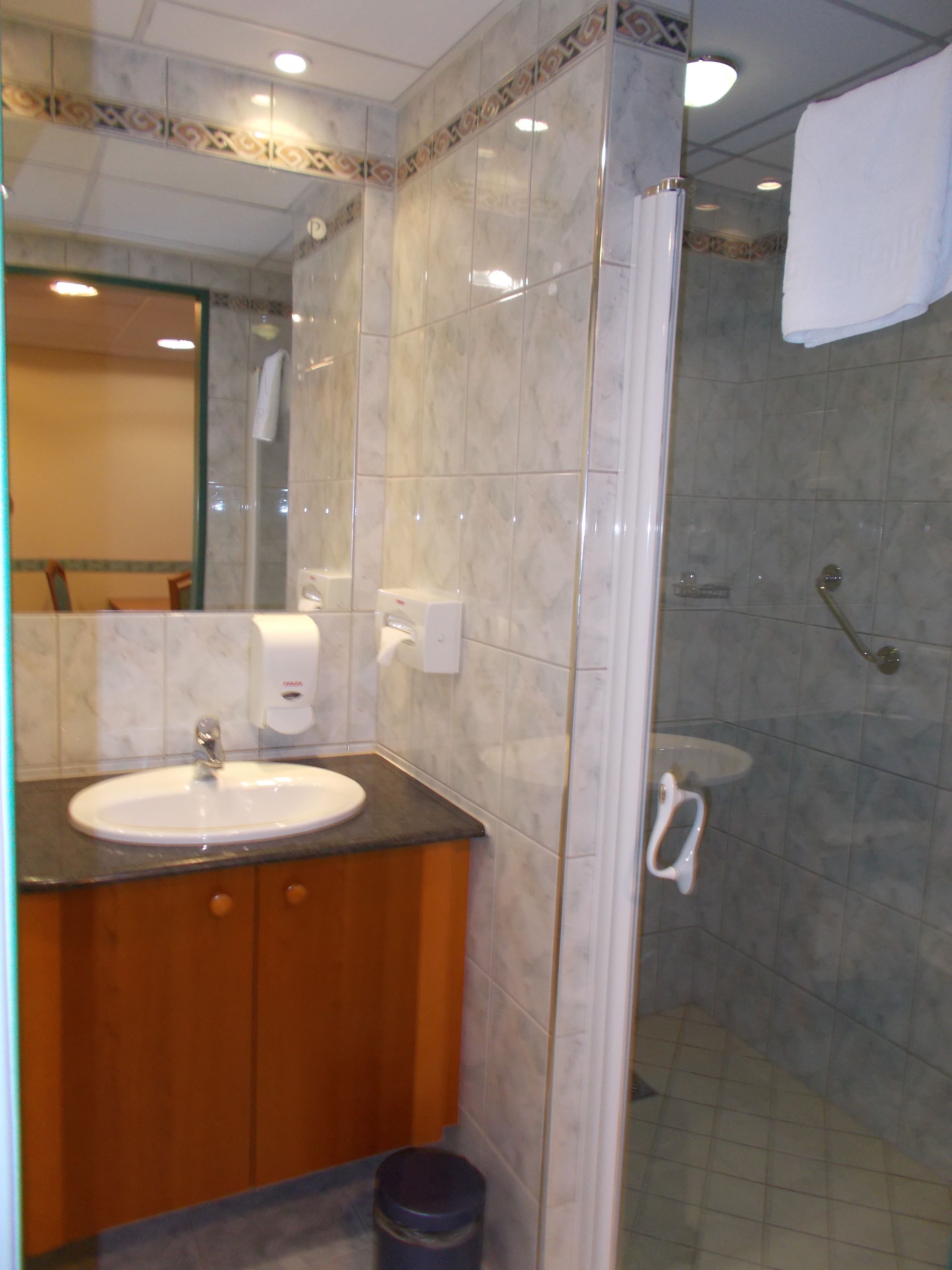 A bathroom with a sink, mirror, and shower.