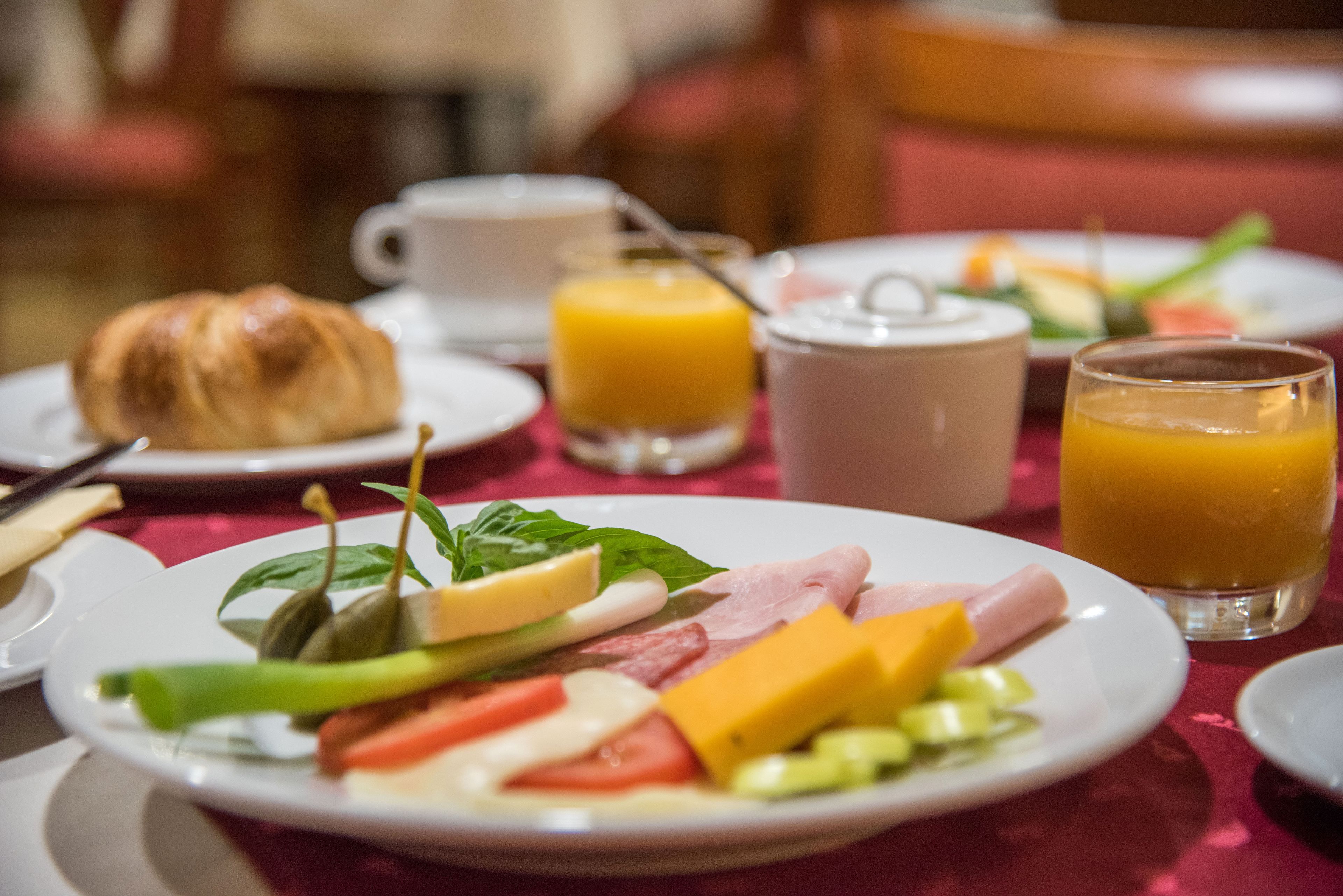 Un desayuno con platos de comida, un croissant y vasos de zumo de naranja.