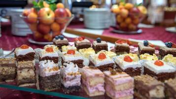 Un tavolo da buffet con diversi dolci e una ciotola di frutta.