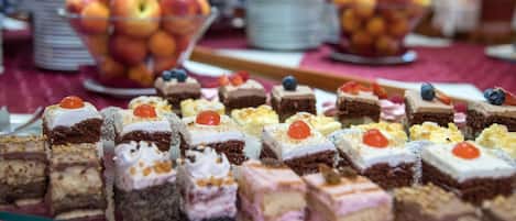 Una mesa de bufé con diversos postres y un tazón de fruta.