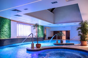 Ein hallenbad mit modernem Design, inklusive einer grünen Wand, Topfpflanzen und einer Wasserattraktion.