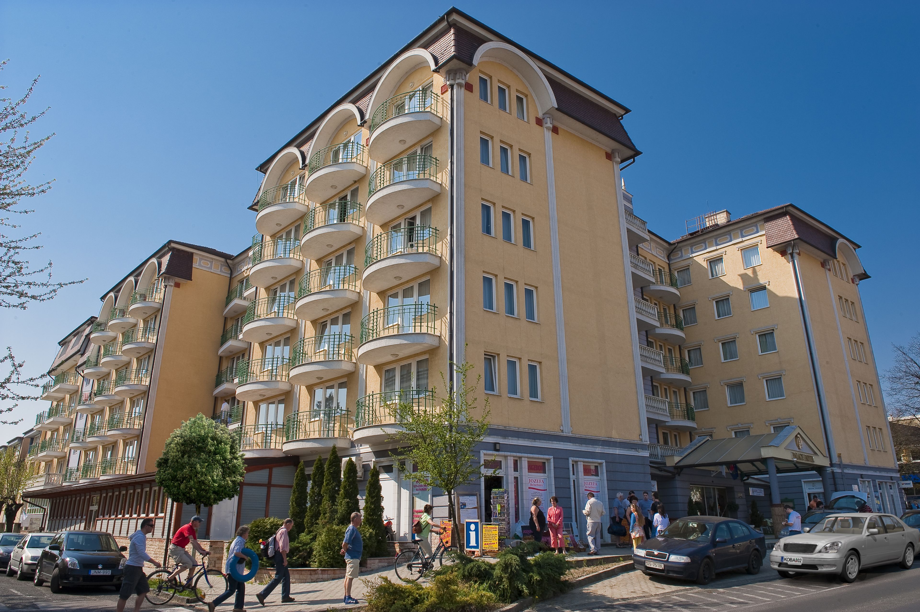 Un hotel a più piani con balconi, un’area di parcheggio e un percorso pedonale.