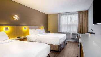 Habitació d'hotel amb dos llits, una escriptori, un televisió de pantalla plana i una finestra amb cortines.