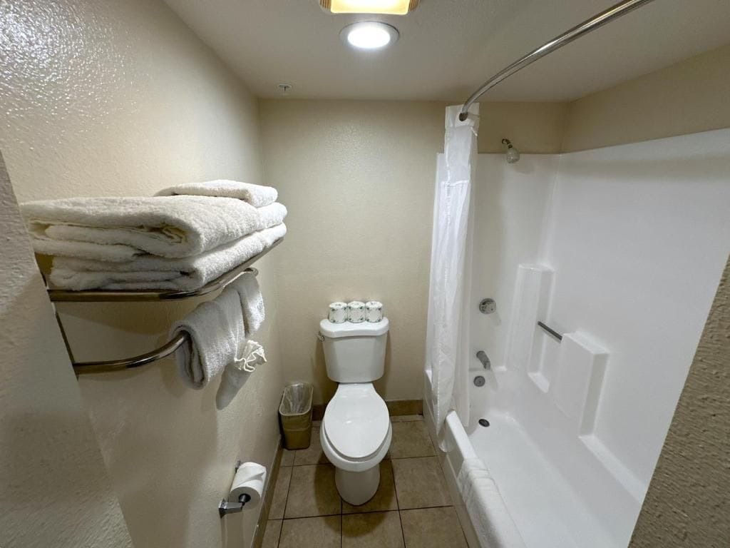 A small bathroom with a toilet, a sink, a shower, and a towel rack.