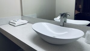 Un baño con un lavamanos blanco, un espejo y una toalla sobre el mostrador.