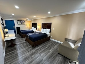 A hotel room with two beds, a desk, and a chair.