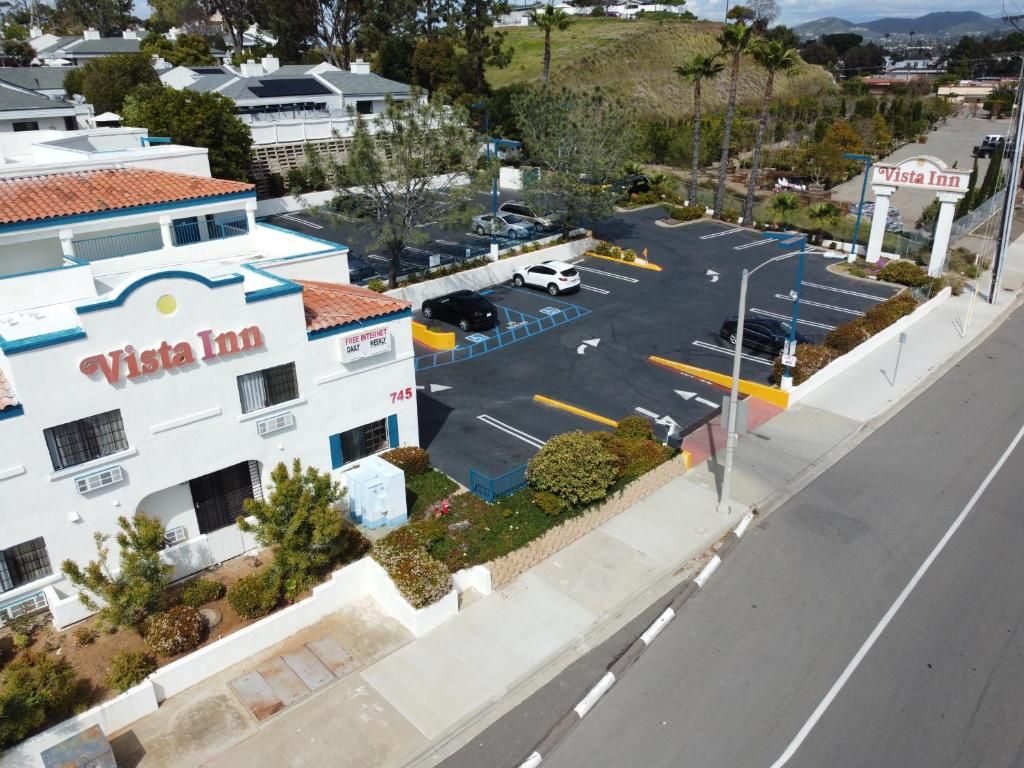 A Vista Inn hotel with a parking lot, a sign indicating the address, and a view of the surrounding area.
