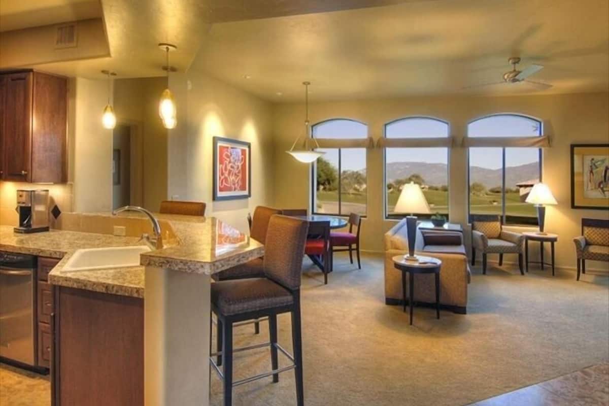 A spacious kitchen with a large island, bar stools, and a dining area with a view.