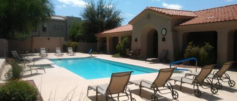 A pool area with lounge chairs and a building with a tiled roof.
