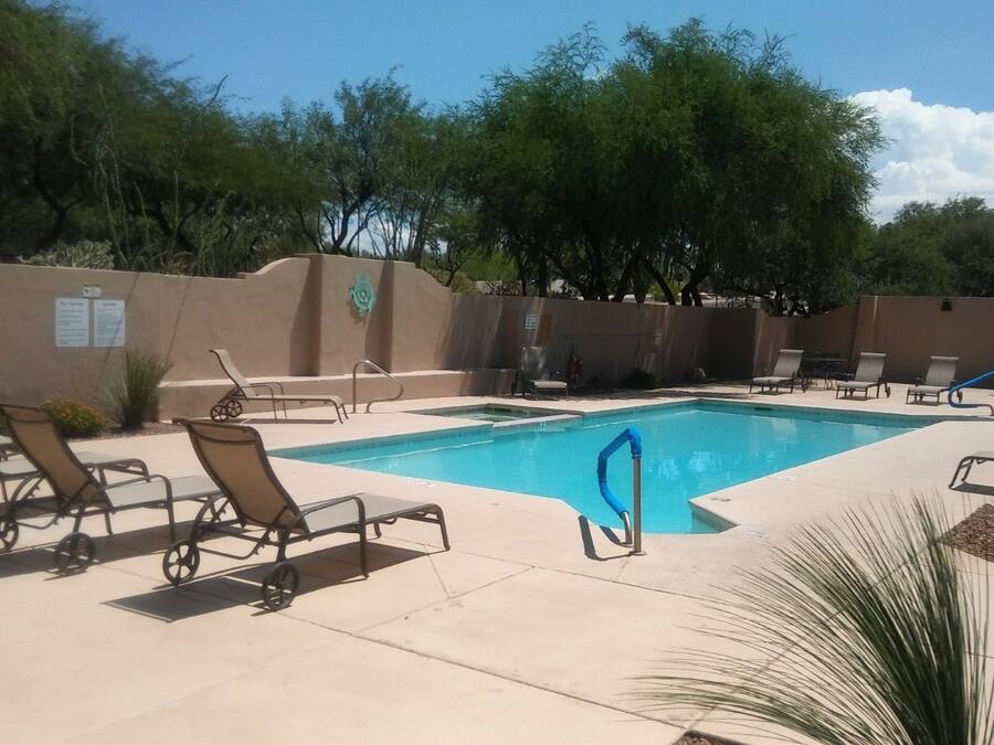 A swimming pool with lounge chairs and a blue slide.